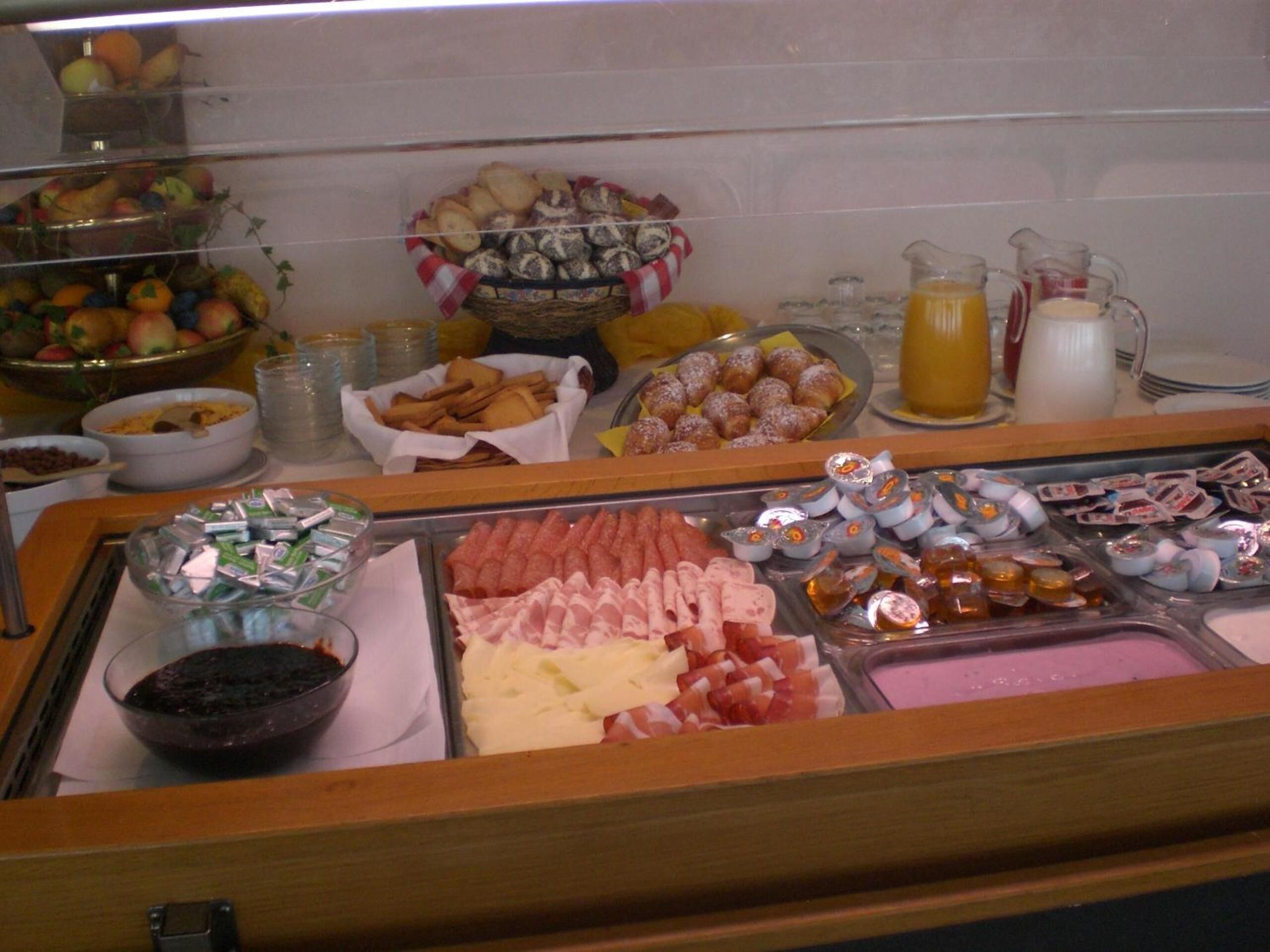 A buffet with various food items including fruits, pastries, and condiments.