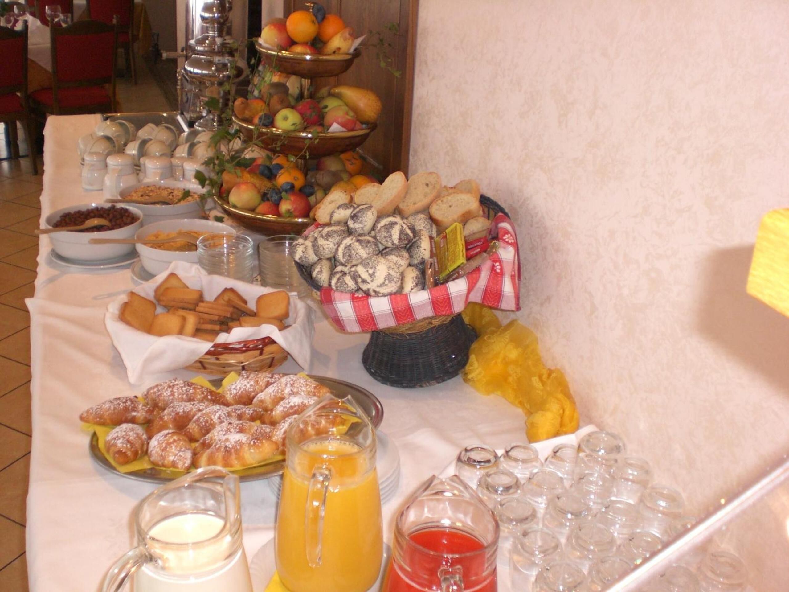 Una mesa de buffet con diversos alimentos, incluyendo frutas, pasteles y bebidas.