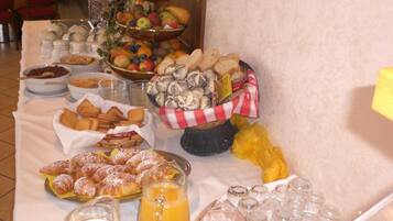 A buffet table with various food items including fruits, pastries, and beverages.