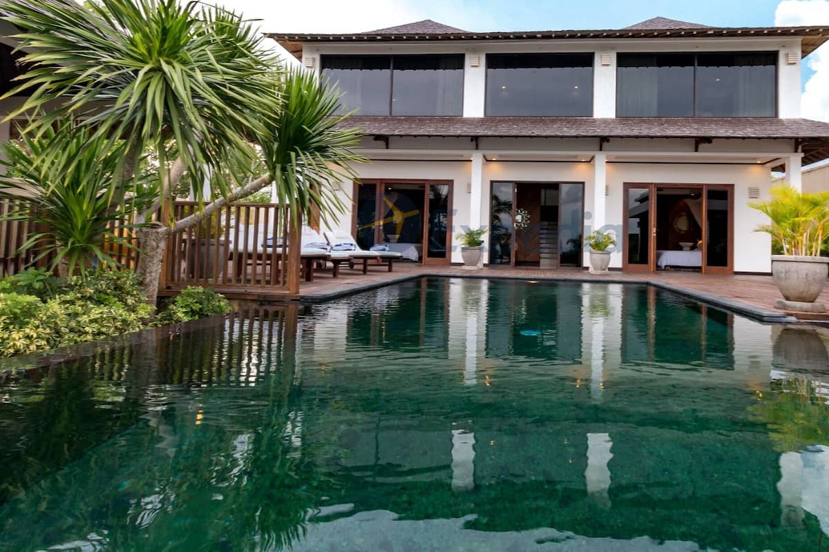 Una casa de dos pisos con piscina al frente.