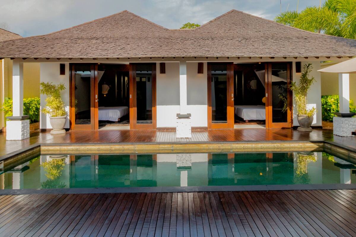 Un resort con piscina, terraza de madera y zonas de estar cubiertas.