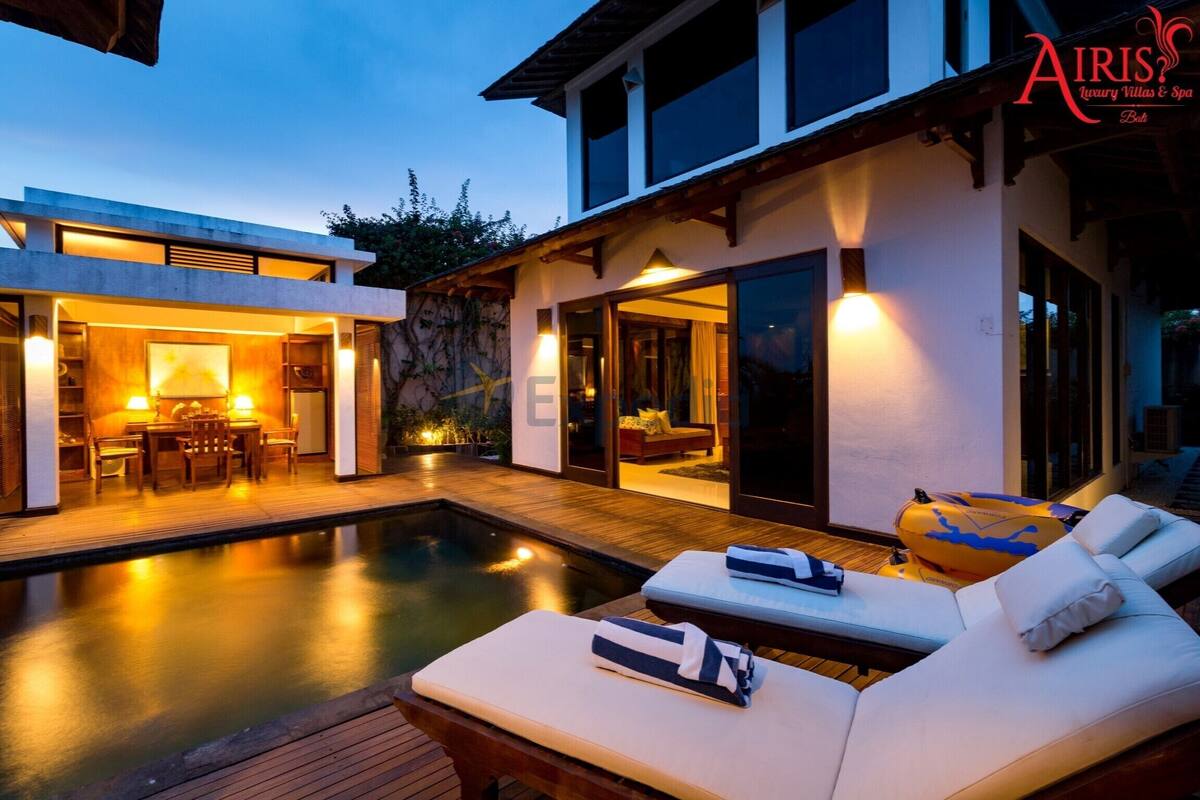 Una villa moderna con piscina, mobiliario exterior e interior bien iluminado.