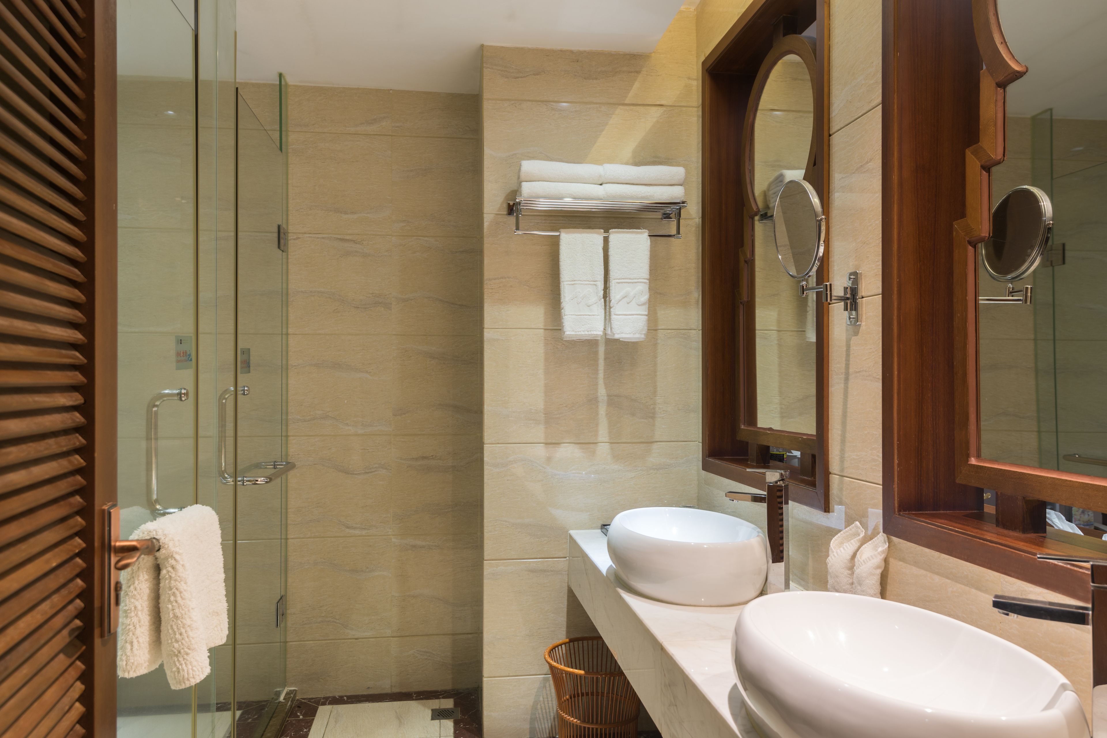 Un bagno moderno con cabina doccia in vetro, un lavandino capiente e due specchi.