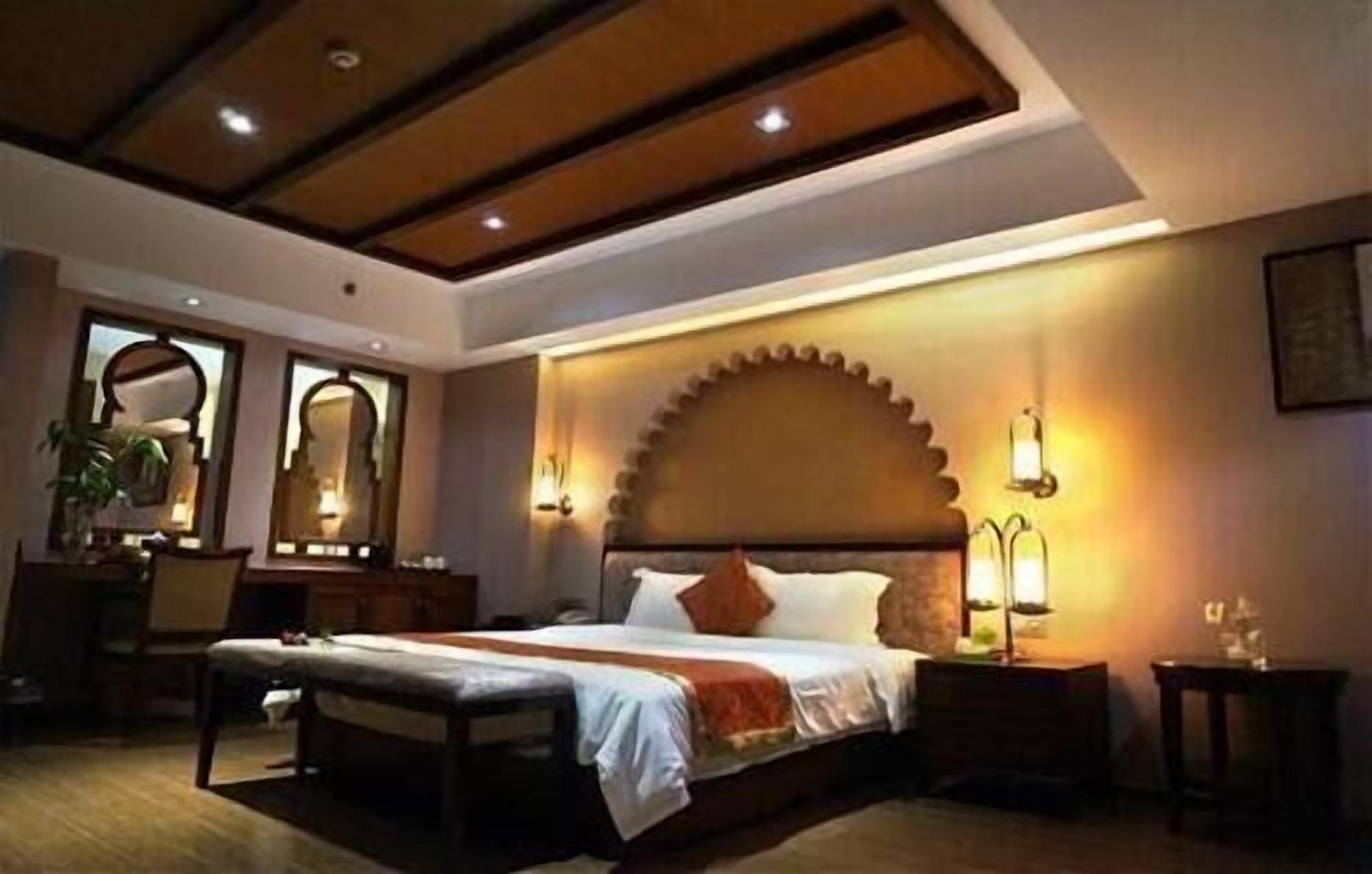 Une chambre d’hôtel avec un grand lit, un plafond en bois et des lampes fixées au mur.