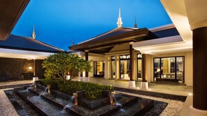 A modern hotel courtyard with a water feature, potted plants, and a traditional architectural style. - Raffles Hainan (Lingshui)