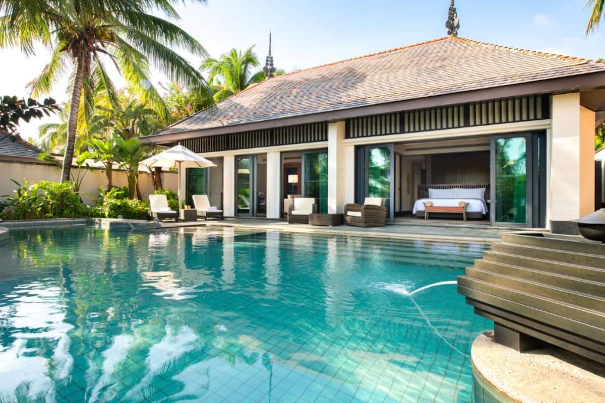 A modern resort with a swimming pool, lounge area with chairs, and a covered seating area.