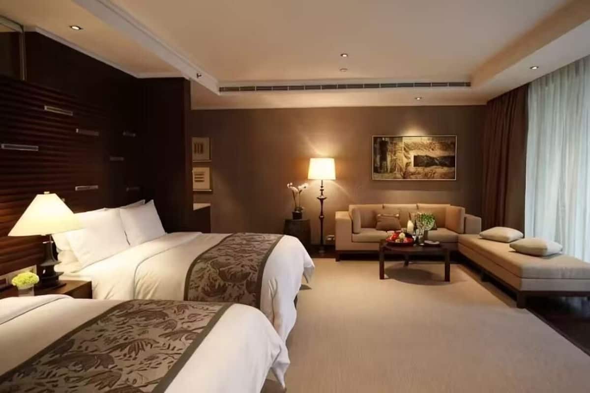 A hotel room with two beds, a sofa, a coffee table, and a painting on the wall.