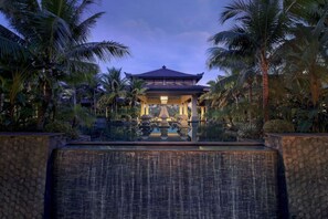 A traditional Japanese-style building with a covered walkway, surrounded by palm trees and a stone wall.