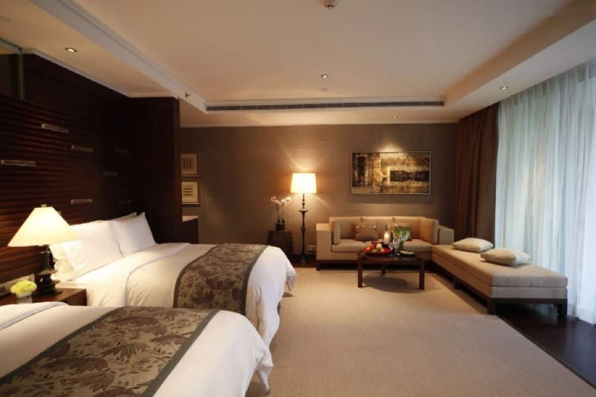 A hotel room with two beds, a sofa, a coffee table, and a painting on the wall.