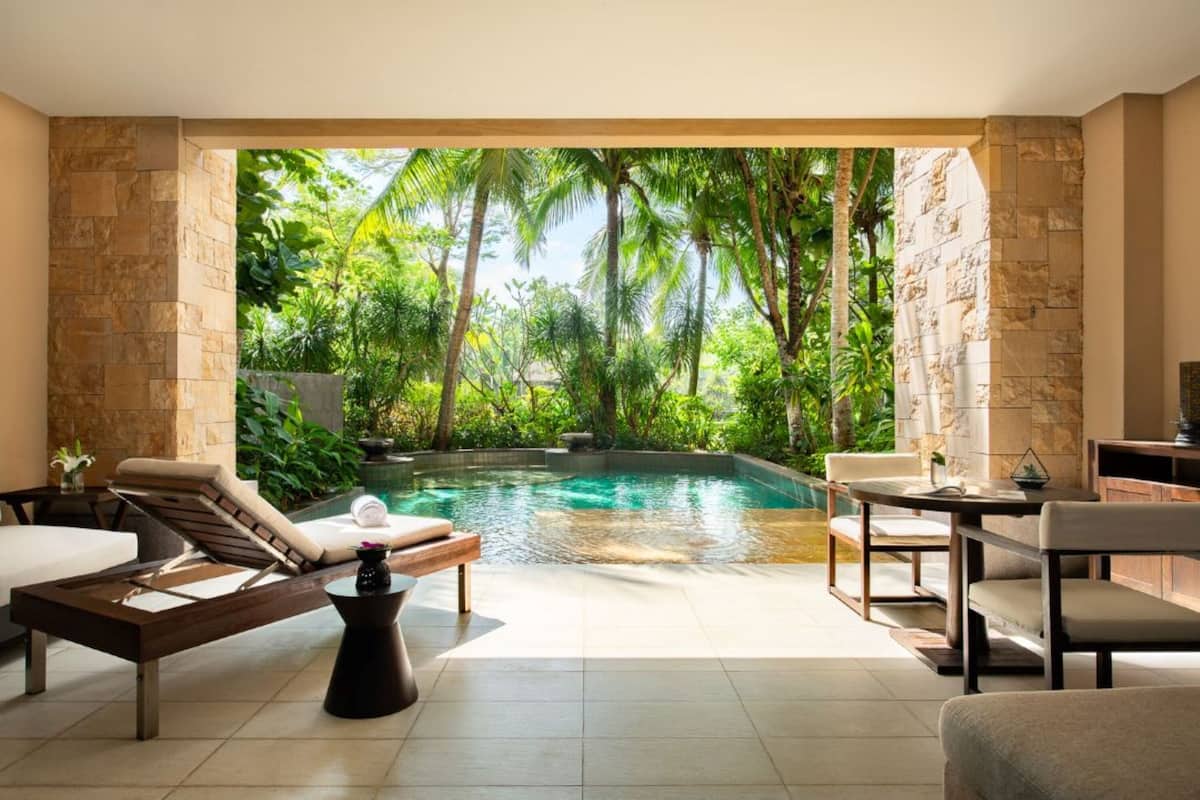 A modern indoor pool area with a view of lush greenery and palm trees.