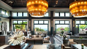 A spacious lobby with large windows, a central seating area, and two large, circular chandeliers. - Raffles Hainan (Lingshui)