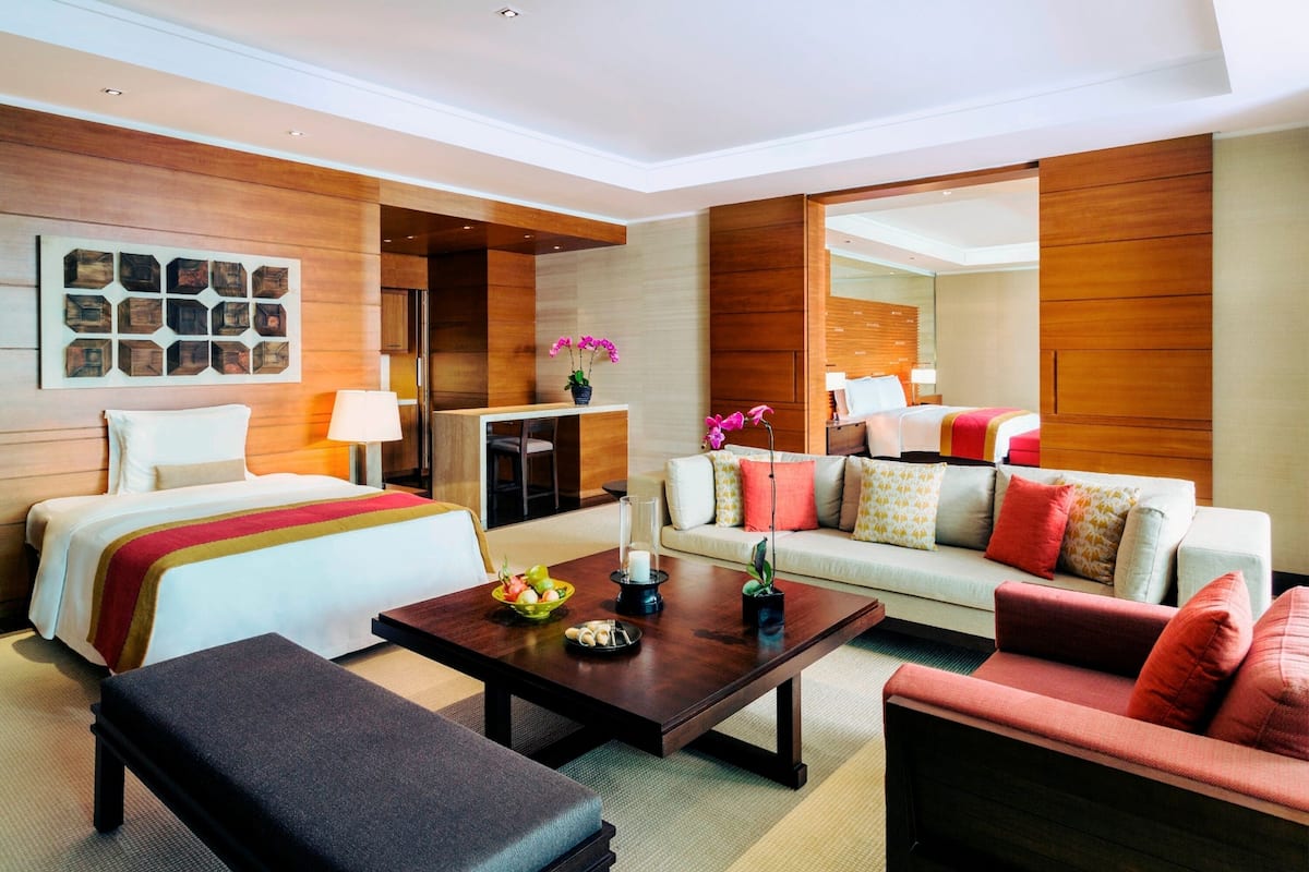 A hotel room with a bed, a sofa, a coffee table, and a desk.