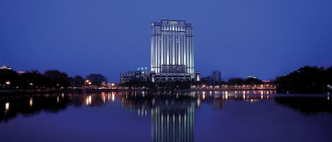 Un edificio alto de diseño moderno que se refleja en aguas tranquilas.
