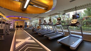 Un gimnasio con cintas de correr, equipo de ejercicio y grandes ventanales con vistas a zonas verdes.
