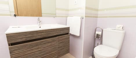 A bathroom with a wooden vanity, a white sink, a toilet, and a mirror above the vanity.
