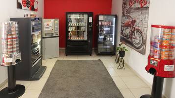 A room with vending machines, a refrigerator, and a motorcycle-themed wall.