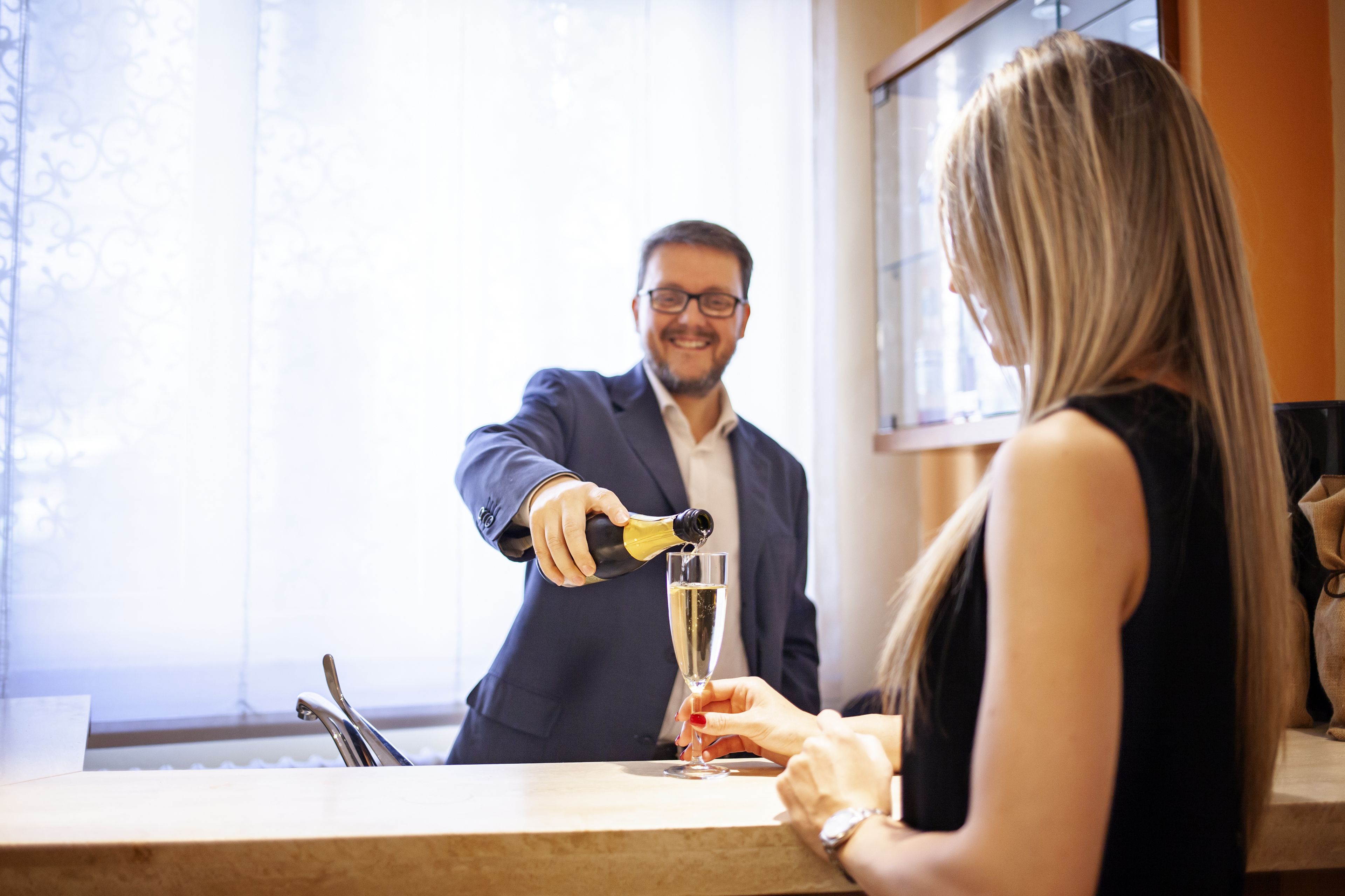 Un hombre sirve champán en una copa que sostiene una mujer en un bar.