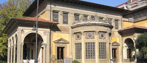 A historic building with classical architecture, featuring columns, arched doorways, and decorative windows.