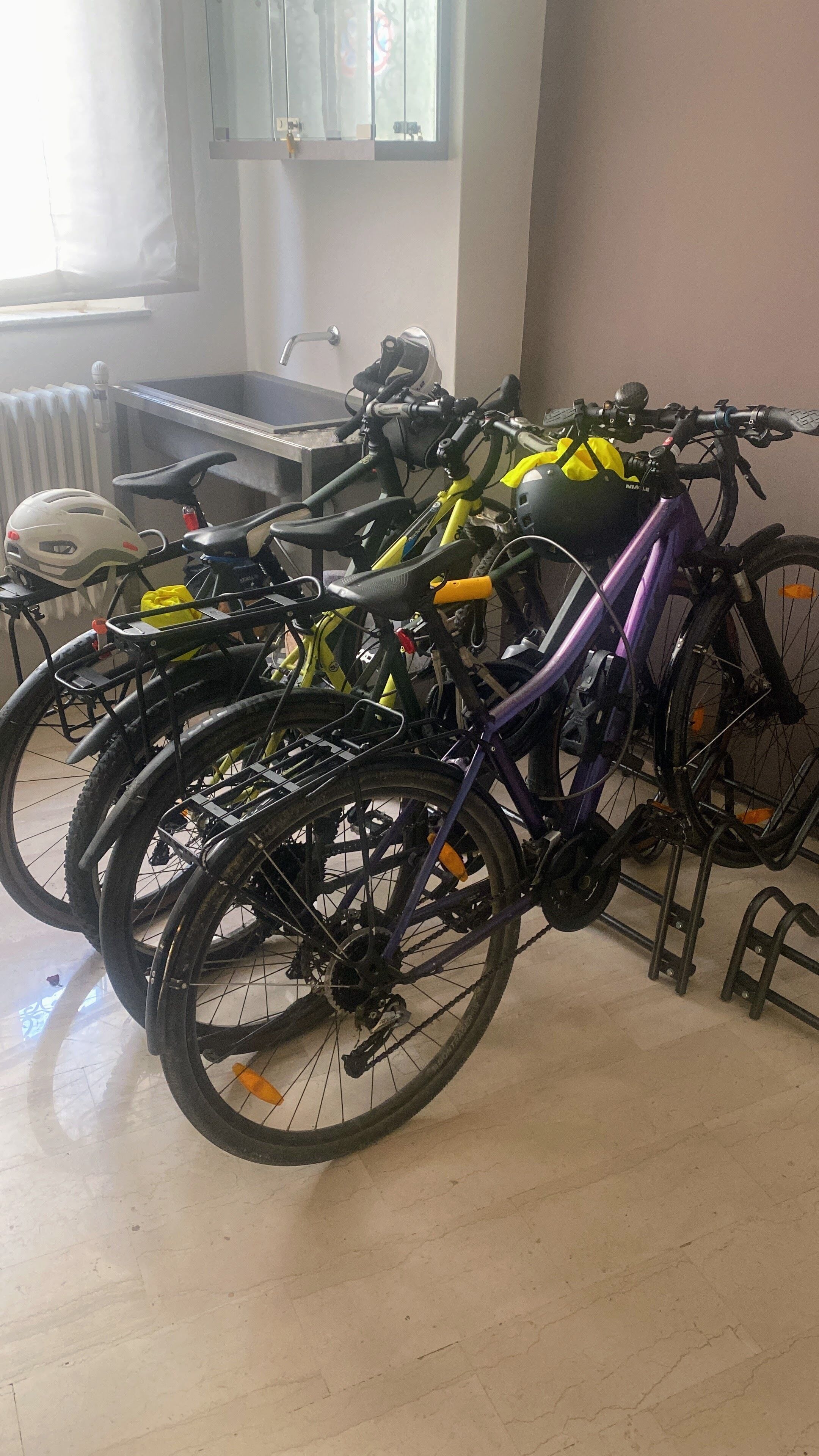 Des vélos sont garés dans une pièce qui contient un radiateur et une fenêtre.