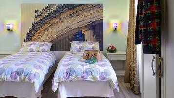 A double bed with a patterned bedspread, a nightstand with a lamp, and a wall mural.