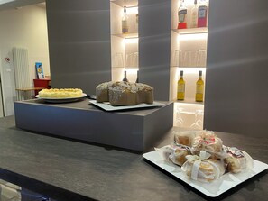 A counter with a cake, bread, and bottles of liquor. - Smart Hotel Bartolini (Montecatini Terme)