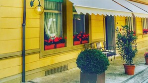 A yellow building with a white awning, green shutters, and a sign for 'Bartolini'. - Smart Hotel Bartolini (Montecatini Terme)