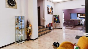 A spacious living area with a staircase leading to a kitchen area. There is a glass display cabinet, a vase with flowers, and a painting on the wall. - Smart Hotel Bartolini (Montecatini Terme)