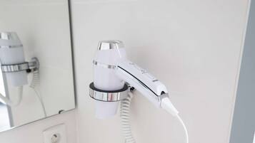 A bathroom with a white sink, a mirror, and a hairdryer mounted on the wall.