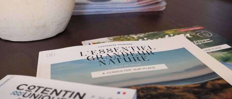 A stack of travel brochures and a vase on a table.