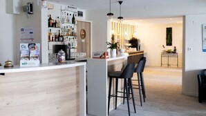 Uma cozinha moderna com bancada de madeira, banquetas e um espaço bar com garrafas e copos.