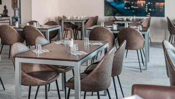 Un espace de restauration moderne, avec des tables et des chaises, une vue sur la ville et un plafond doté d’un éclairage encastré.