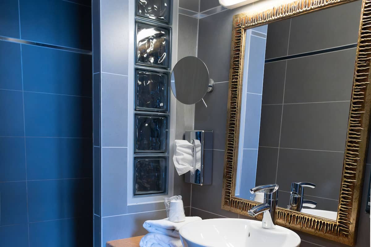 A modern bathroom with a large mirror, a white sink, and a shower area.