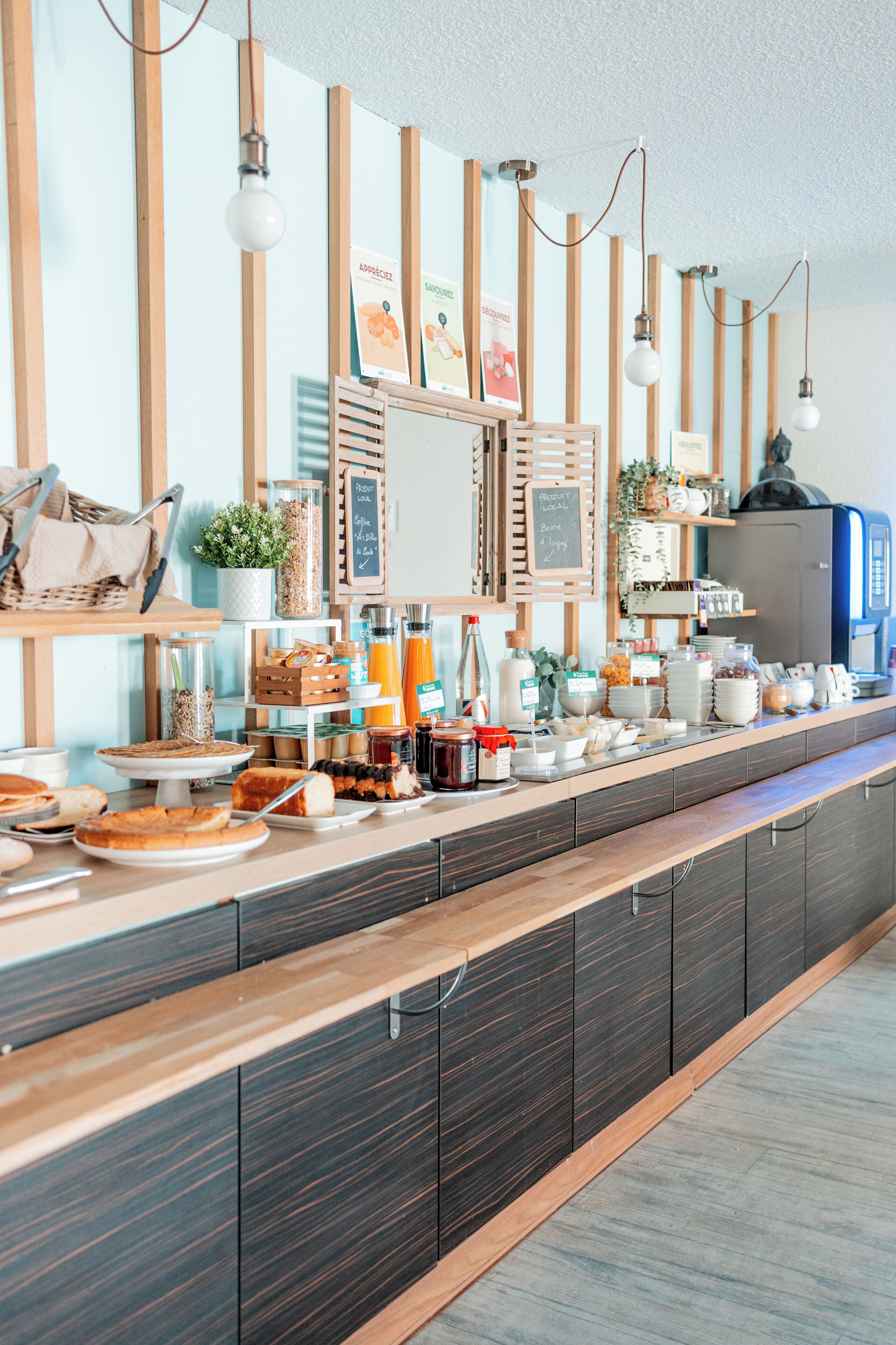 A breakfast buffet with various food items and beverages, wooden paneling, and hanging light fixtures.