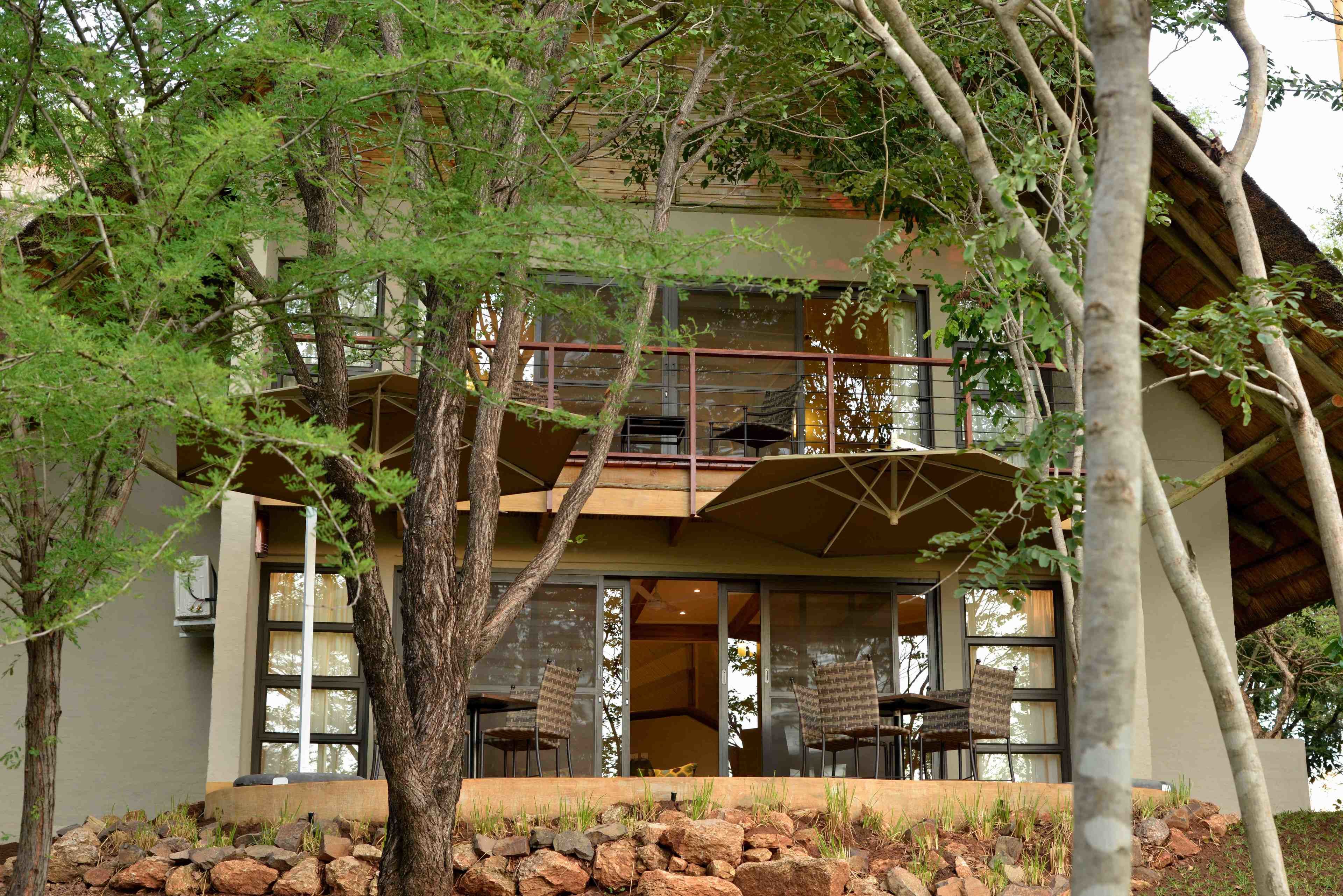 A two-story building with a balcony, large windows, and outdoor seating.