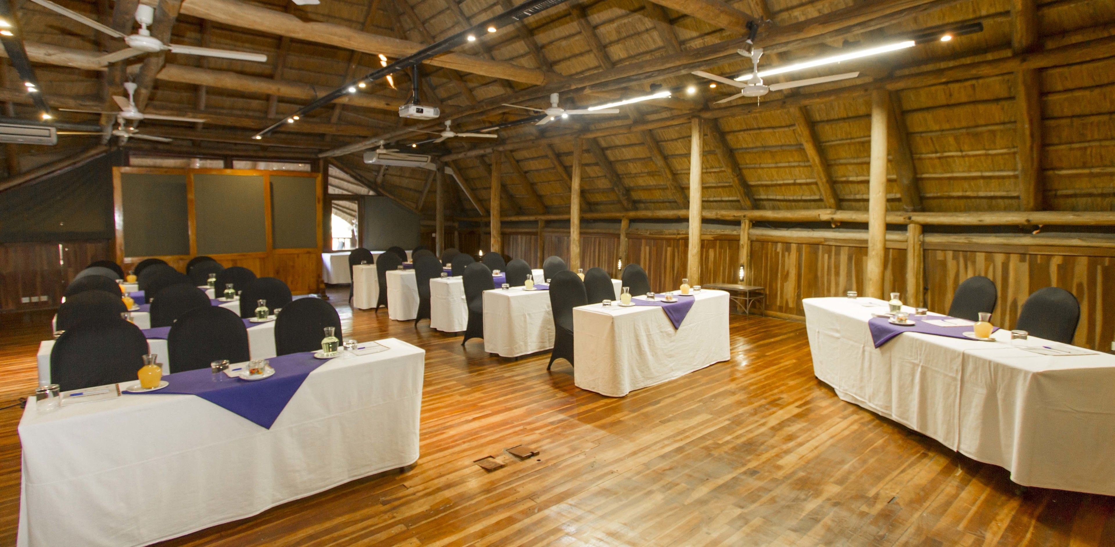 A conference room with multiple tables, chairs, and a projector screen.