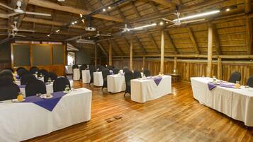 A conference room with multiple tables, chairs, and a projector screen.