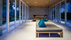 Een modern interieur met een lange bank, een houten bureau en een uitzicht door grote glazen deuren.