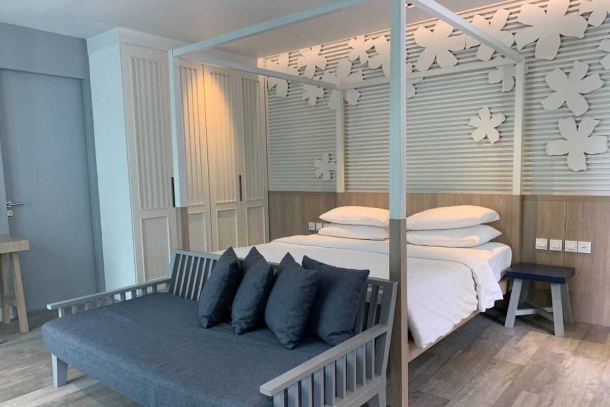 Une chambre à coucher moderne avec un lit, un banc et un mur décoratif.