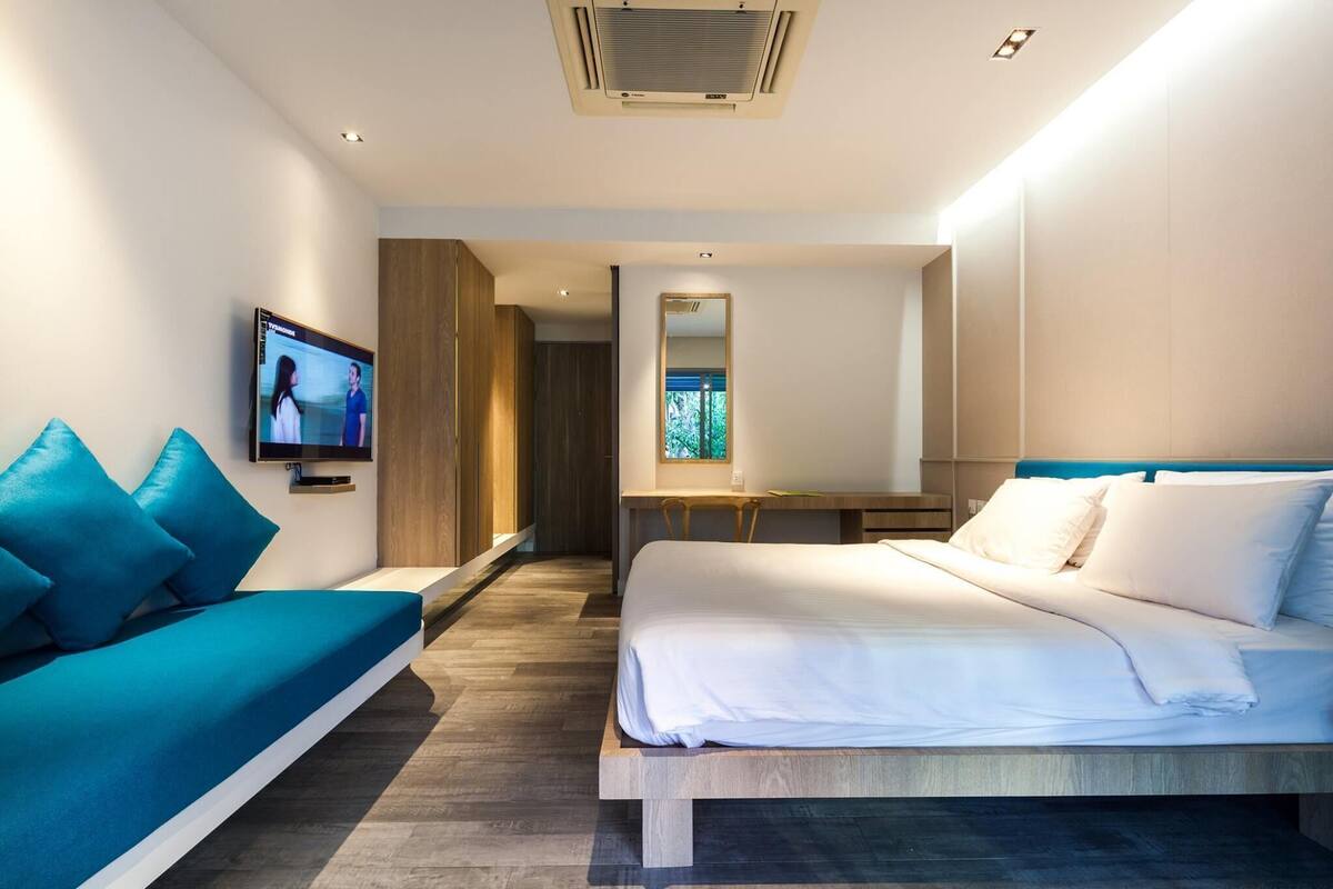 Une chambre d’hôtel moderne équipée d’un lit, d’un canapé, d’une télévision et d’un bureau.