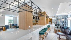 Un moderno bar con techo alto, detalles de madera y una larga barra con taburetes.