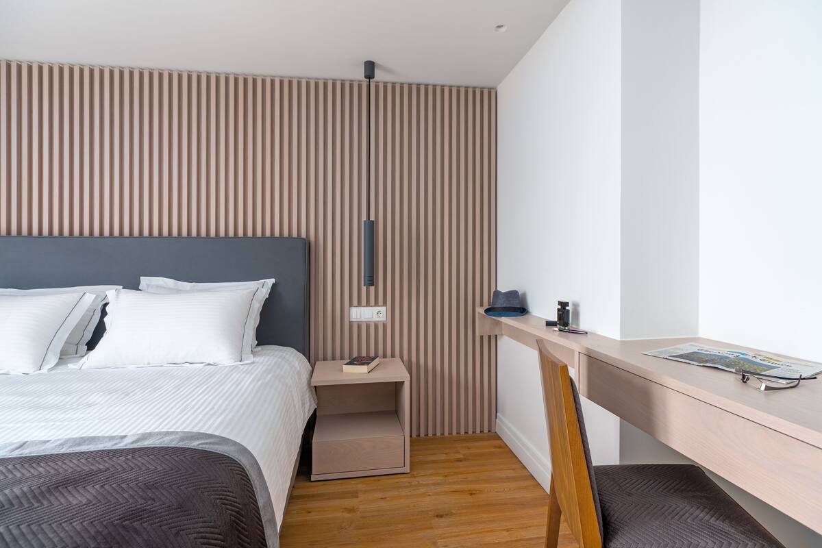 A modern bedroom with a bed, bedside table, and a desk with a chair.