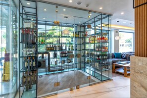 A modern interior with glass display cases of various bottles, a leather sofa, and a wooden reception desk.
