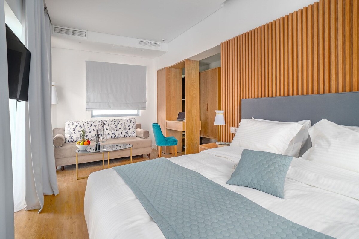 Una habitación de hotel moderna con una cama grande, un escritorio, un sofá y un televisor.