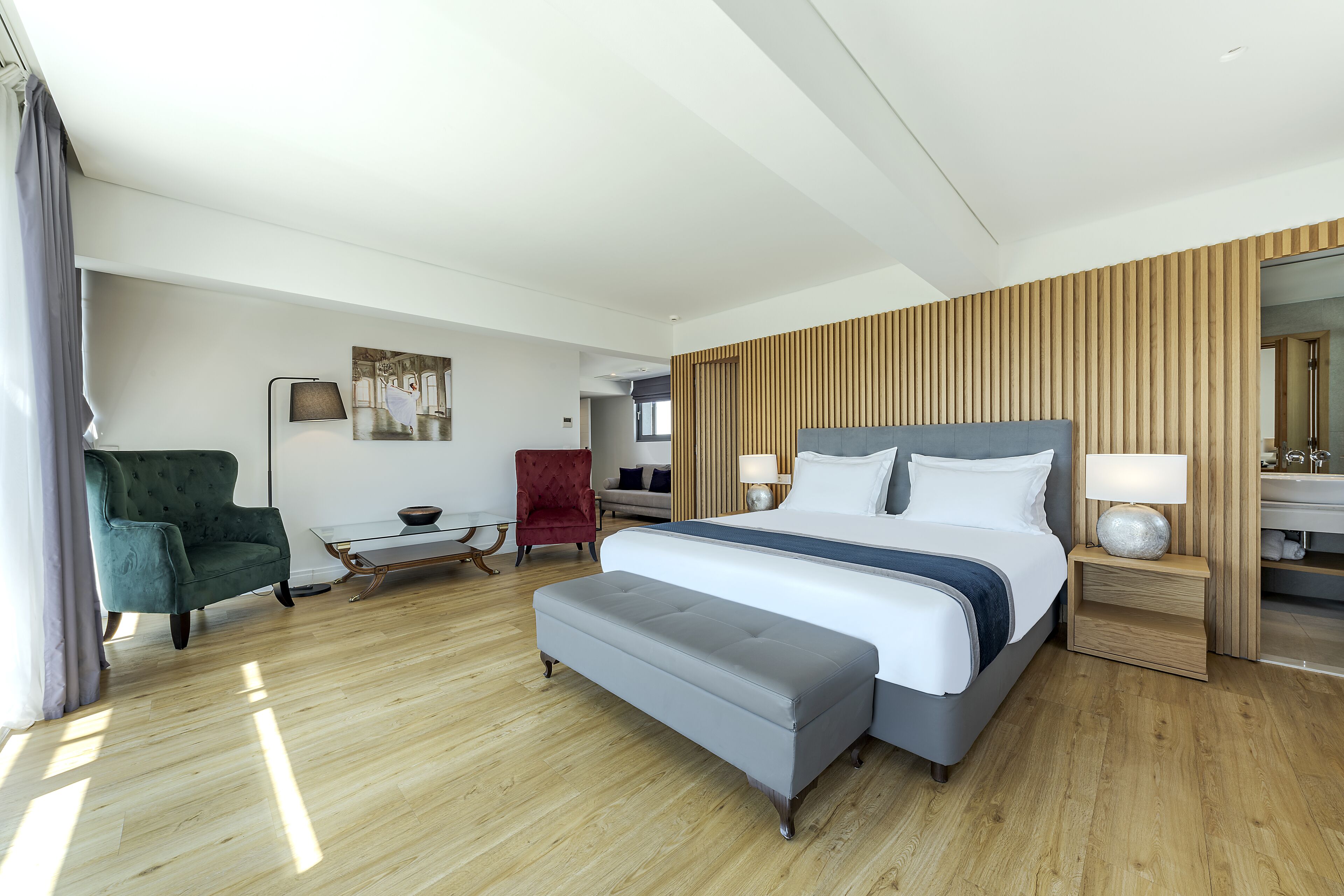 Una habitación de hotel moderna con una cama grande, un banco, un escritorio y una silla.