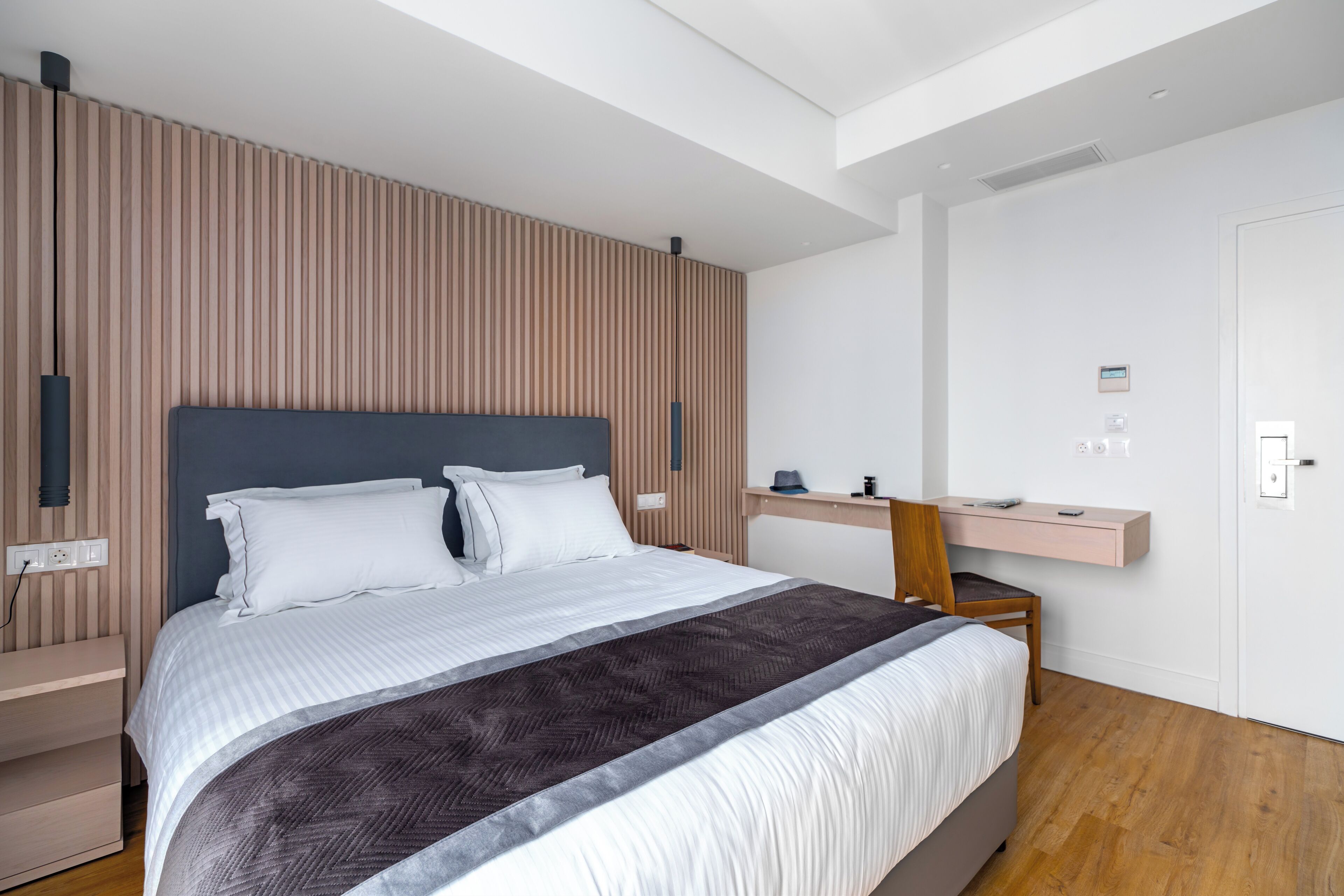 Habitació d'hotel moderna amb un llit gran, una taula de treball i una cadira.
