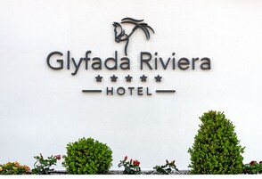 Un letrero de hotel con el nombre 'Glyfada Riviera HOTEL' y un logotipo de palmera.