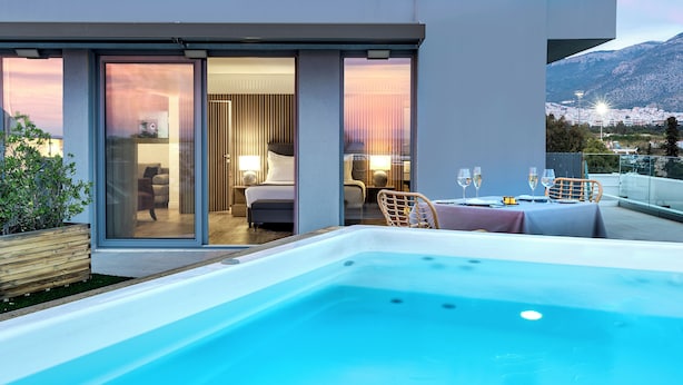 Un hotel moderno con una sala acristalada, un jacuzzi y una mesa para dos con copas.