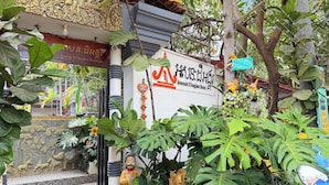 A hotel entrance with a sign in a foreign language, surrounded by lush greenery and decorative elements.
