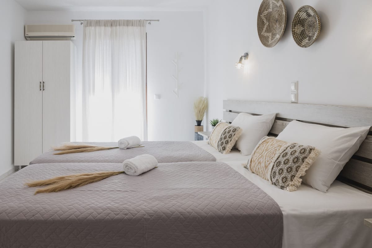 Un dormitorio con dos camas, un armario, una ventana con cortinas y adornos en la pared.