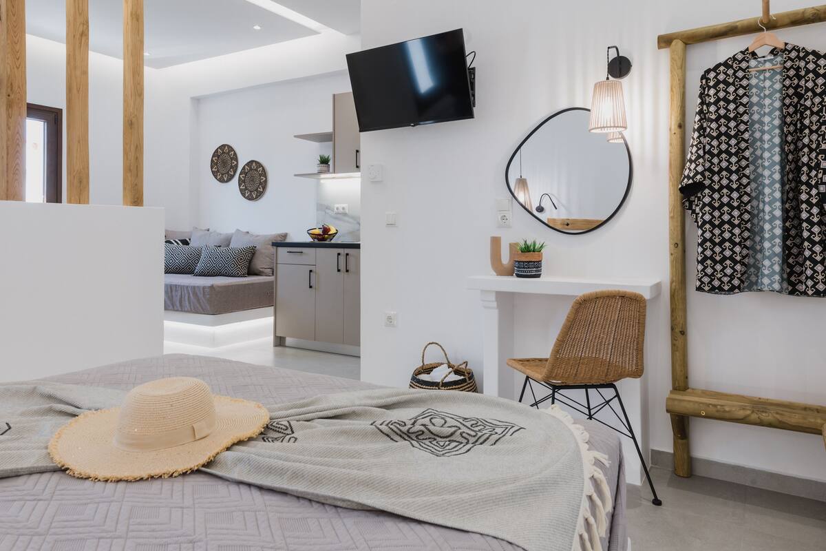 Un dormitorio moderno con cama, televisor, espejo y armario.